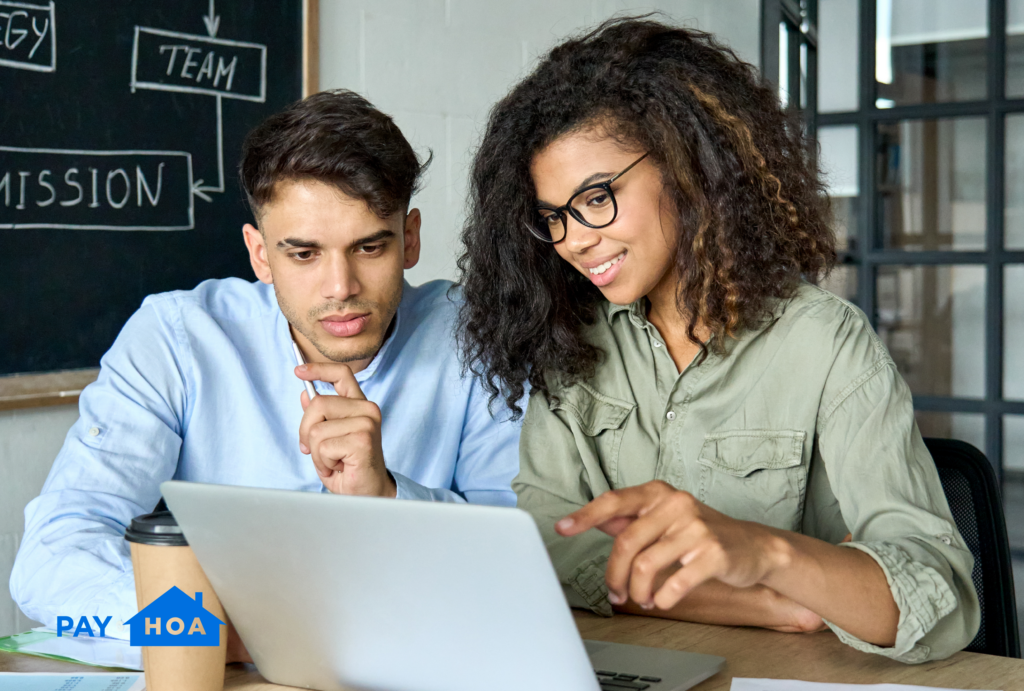 Two volunteer board members using HOA management accounting software on a laptop