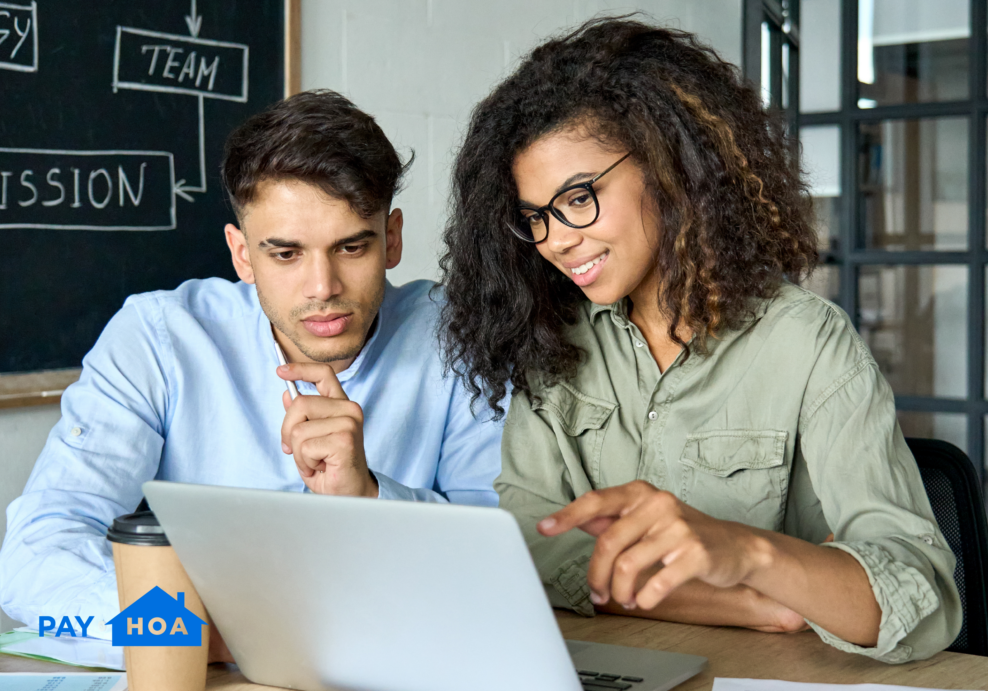 Two volunteer board members using HOA management accounting software on a laptop